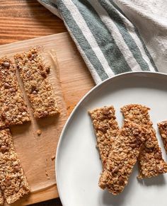 several pieces of granola on a plate next to a cutting board