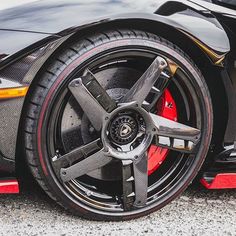 the front wheel of a sports car with red brake pads and black rims on it