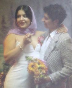 a man in a suit and tie standing next to a woman wearing a wedding dress