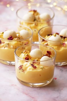 four desserts in small glass dishes on a marble table with gold lights behind them