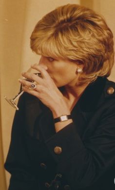 a woman holding a wine glass in her right hand and looking off to the side