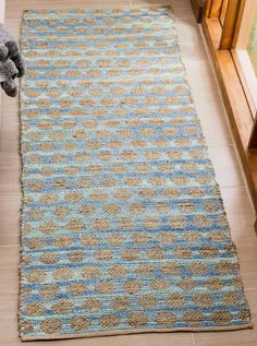 a blue and beige rug on the floor next to a window with a teddy bear