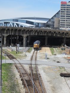 a train is coming down the tracks in front of an empty station with tall buildings