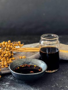 a bowl of soy seeds next to a jar of oil and some chopsticks