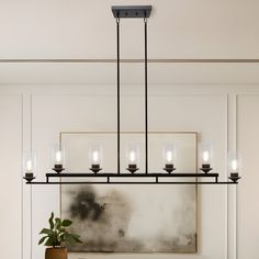 a chandelier hanging over a dining room table with chairs and a potted plant