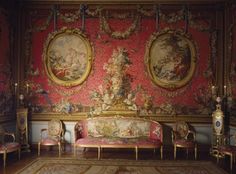 an ornately decorated room with two couches and paintings on the wall behind them