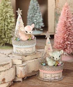 two tin canisters decorated with christmas trees and small animals sitting on top of them