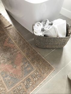 a bath tub sitting next to a rug in a bathroom