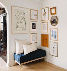 a blue couch sitting in front of a wall filled with framed pictures on it's side