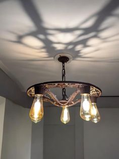 a chandelier with three light bulbs hanging from it's center and shadow on the ceiling