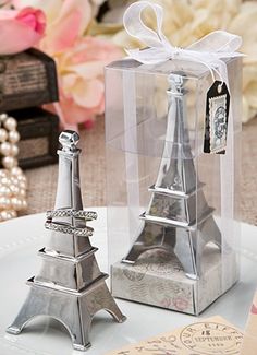 two small silver metal eiffel tower figurines on a plate