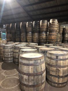 many wooden barrels are stacked up in a room with sunlight coming through the roof and floor