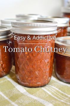 jars filled with tomato chutney sitting on top of a table