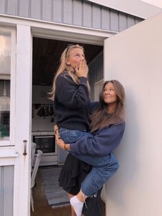 two women leaning against the side of a building