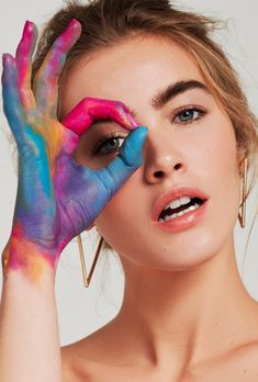 a woman with her hands painted in bright blue and pink, posing for the cover of color magazine