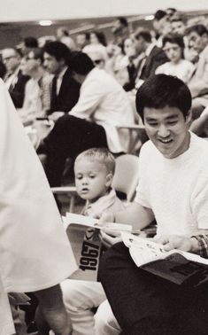 a young man sitting next to a little boy in front of a crowd of people