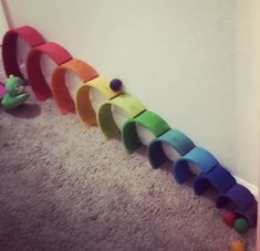 a rainbow colored wall hanging on the side of a white wall next to a teddy bear