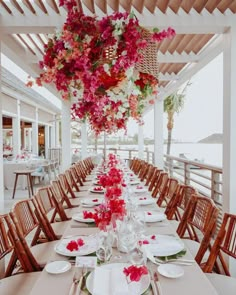 an outdoor dining area with tables and chairs covered in pink flowers hanging from the ceiling