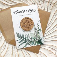 save the date magnets with greenery and leaves on them are sitting on top of a brown envelope