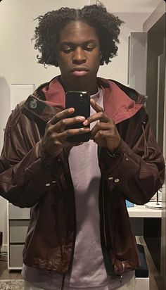 a man is taking a selfie in the mirror with his cell phone while wearing a brown jacket