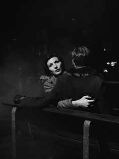 two people sitting on a bench in the dark