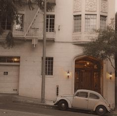 an old car parked in front of a white building with stairs on the second floor