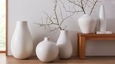 three white vases sitting next to each other on a table