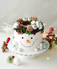 a cake decorated with flowers and snowmen on top of a white plate next to christmas decorations