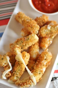 some fried food on a white plate next to a small bowl of ketchup