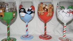 four wine glasses with different designs and colors are lined up on a white surface, one has a candy cane