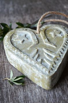 a heart shaped soap with two faces carved into it and tied up to a string