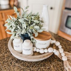 a wooden tray topped with bottles next to a potted plant on top of a counter