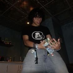 a young man is holding several bottles in his hands and wearing a skull t - shirt