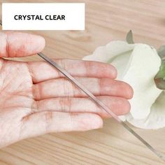 a hand holding a pair of scissors with a flower in the background that reads, odouless transparentent 1 5mm thickness