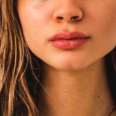 a close up shot of a woman's face with her nose ring in gold