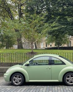 a small green car parked in front of a fence