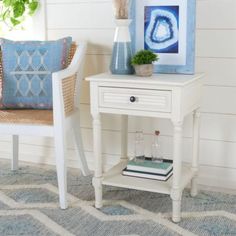 a white table with a blue and white painting on the wall next to a chair