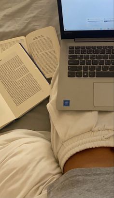 an open laptop computer sitting on top of a bed next to two book's