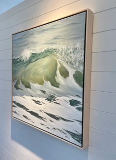 a painting hanging on the side of a white wall next to a wooden frame with waves in it