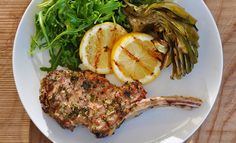 a white plate topped with meat and veggies on top of a wooden table