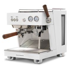 an espresso machine sitting on top of a white counter next to a wooden handle