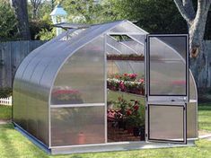 a small greenhouse in the middle of some grass