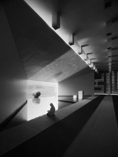 a black and white photo of a person sitting on the ground in front of a wall