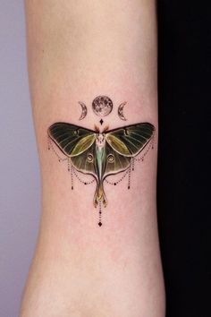 a small moth tattoo on the ankle with stars and crescents around it's wings