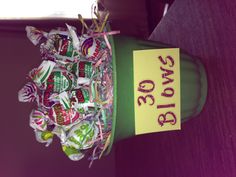 a green pot filled with lots of lollipops on top of a table