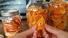 a person is holding an orange peel in front of some jars filled with sliced oranges