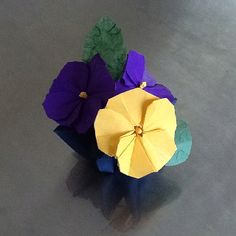 three origami flowers sitting on top of a gray table next to each other