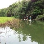 three people are paddling down the river on their paddles and one person is standing in the water