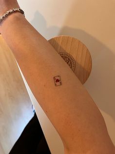 a woman's arm with a small red and white heart tattoo on the wrist