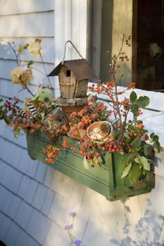 a bird house sitting on top of a window sill filled with plants and berries